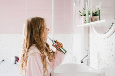 Cute girl in a pink bathrobe brushes her teeth in a bathroom hygiene concept