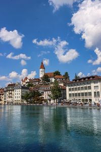 Buildings at waterfront against cloudy sky