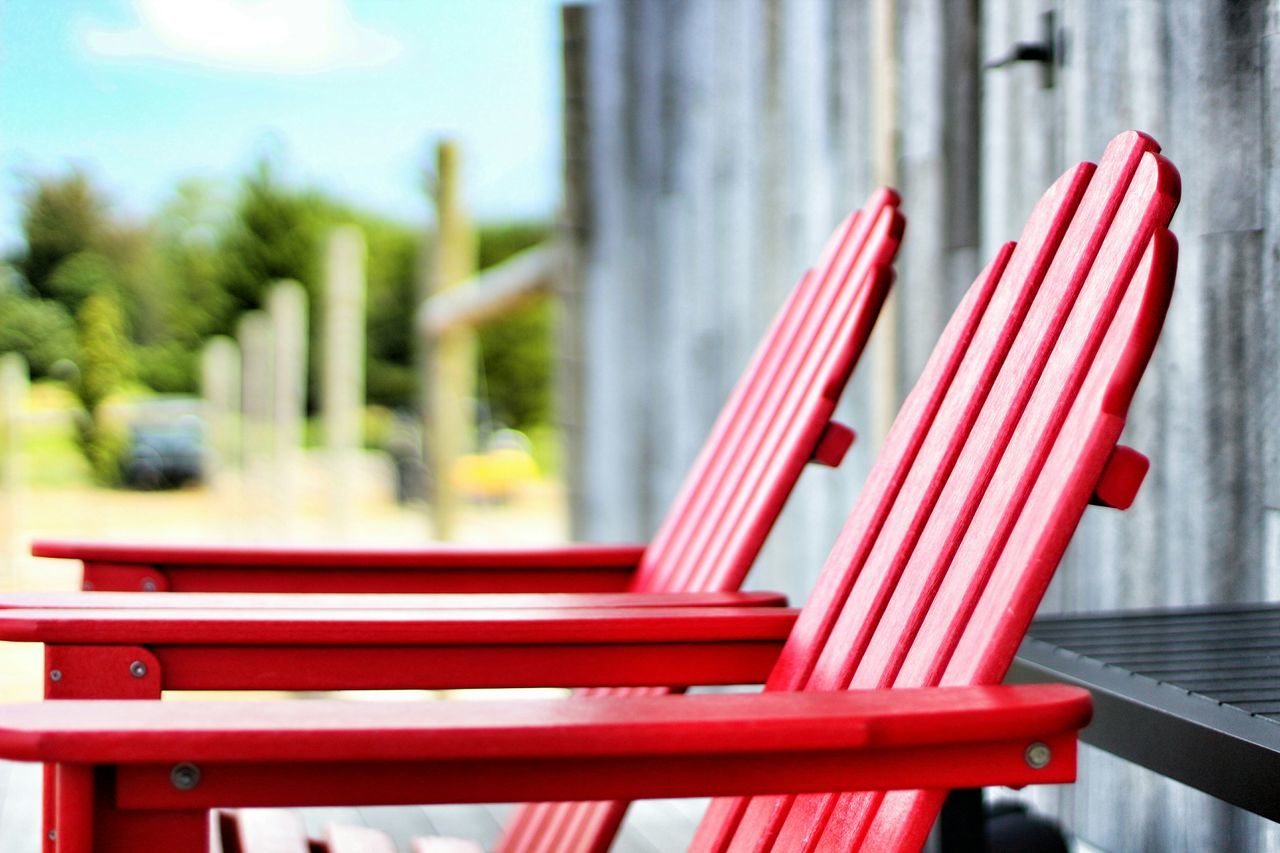 red, focus on foreground, close-up, wood - material, wooden, day, selective focus, outdoors, flower, no people, bench, railing, wood, pink color, table, built structure, park - man made space, chair, nature, growth