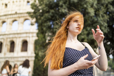 Thoughtful traveler with smartphone on windy day