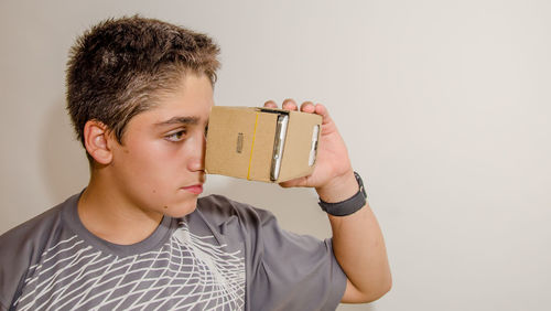 Boy watching virtual reality against gray background