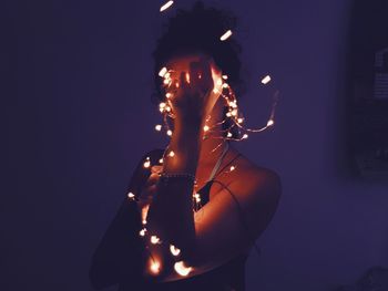 Close-up of woman illuminated string lights