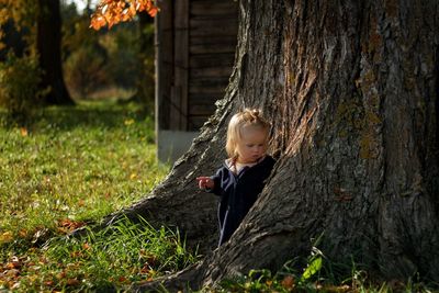 Girl standing by tree trunk