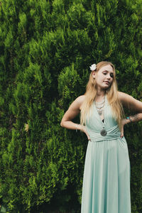 Beautiful young woman standing against plants