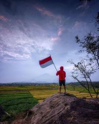 Rear view of man standing on field against sky
