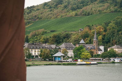 Houses by trees and buildings against mountains