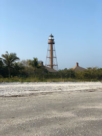 Lighthouse by land against clear sky