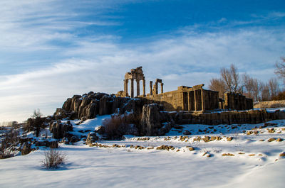 Low angle view of old ruins on snow covered field at baalbek