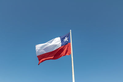 Low angle view of flag against clear blue sky