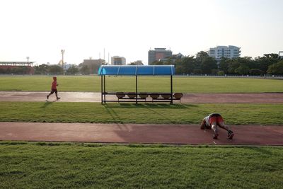 Rear view of people playing field against clear sky