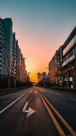 Empty road along buildings at sunset