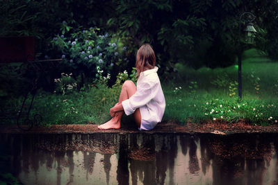 Rear view of woman sitting by lake