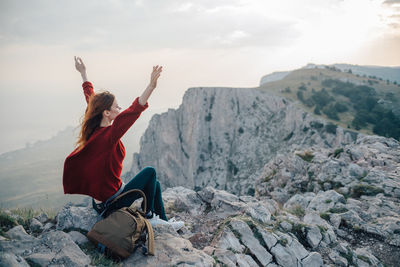 Man sitting on rock against mountains