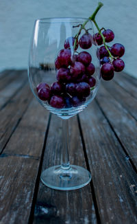 Close-up of grapes in wineglass on wooden table