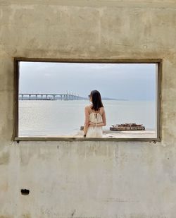 Side view of young woman standing against wall
