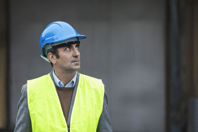 Mature worker wearing protective workwear looking away at factory