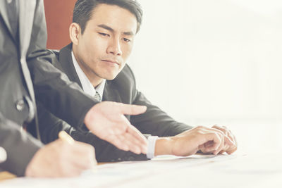 Midsection of businesswoman explaining to businessman in office