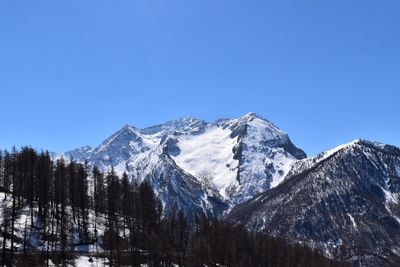 Scenic view of snowcapped mountains against clear blue sky