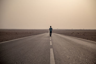 Rear view of man on road against sky