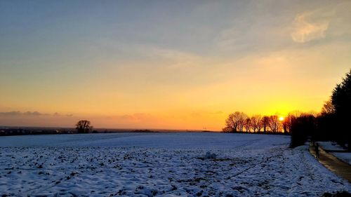 Scenic view of snow covered field against sky during sunset