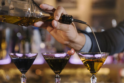 Cropped hands of male bartender preparing cocktail at bar counter