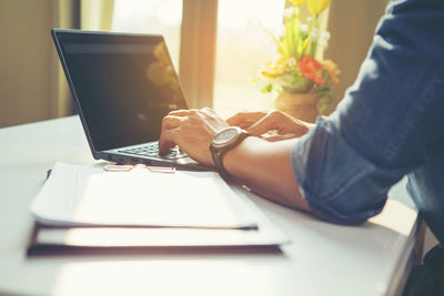 Midsection of man using laptop on table