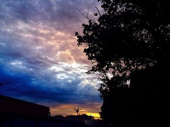 Low angle view of silhouette trees against cloudy sky