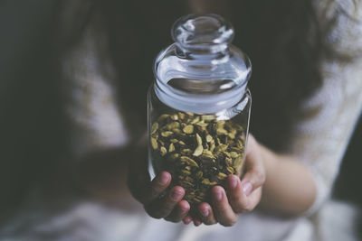 Close-up of woman holding cinnamon and spices in jar