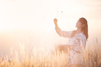 Woman standing on field against sky during sunset