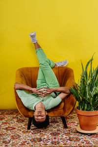 Man sitting upside down on armchair in studio