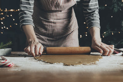 Woman rolls out the dough with a rocking chair for extruding and cutting out gingerbread cookies