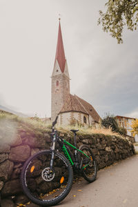 Bicycle by building against sky