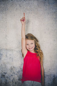 Portrait of a smiling girl standing against wall