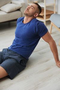 Side view of man exercising on floor at home