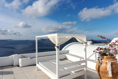 Deck chairs by sea against sky