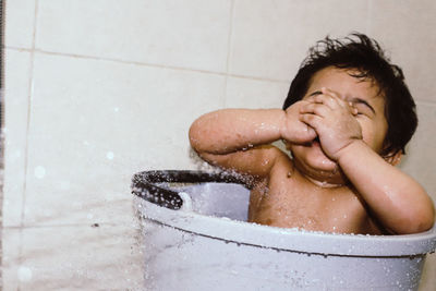 Full length of boy enjoying a bath playing with water