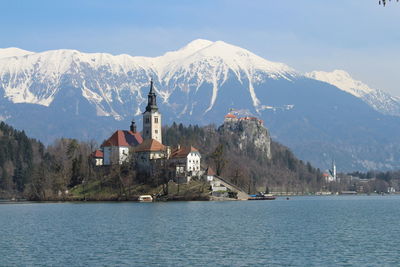 Church by lake against snowcapped mountain