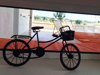 Bicycle parked by window against sky