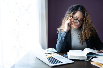 Young woman using phone while sitting on table