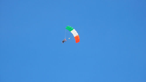 Low angle view of person paragliding against clear blue sky