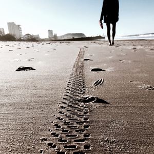 Tire track by person walking on sandy beach