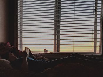 Woman reading while lying on sofa at home