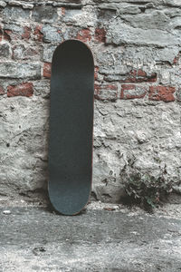 Close-up of skateboard by weathered wall