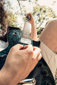 Low section of man holding guitar