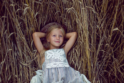 Blonde girl lying on the field among the dry ears of wheat in the summer