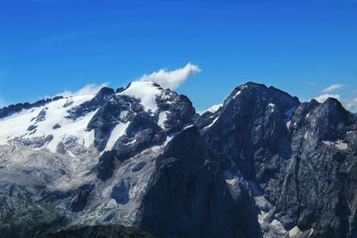 Low angle view of snowcapped mountains against blue sky