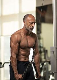 Shirtless man exercising in gym