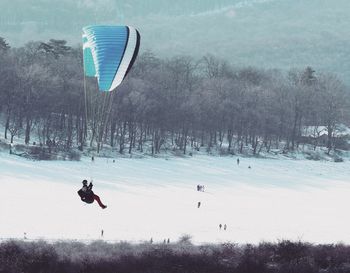 Person paragliding in snow against sky
