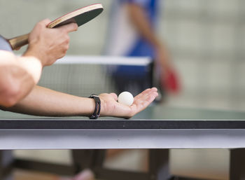 Cropped hands of man playing table tennis