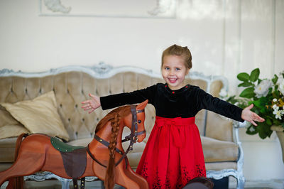 Beautiful little girl with a toy wooden horse in a vintage studio.